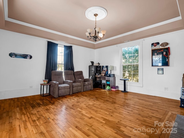 interior space with a chandelier, a raised ceiling, ornamental molding, and hardwood / wood-style flooring