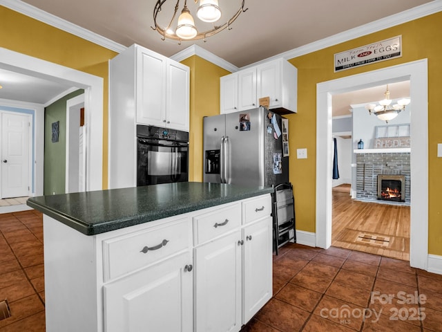 kitchen featuring crown molding, dark countertops, white cabinetry, black oven, and stainless steel fridge