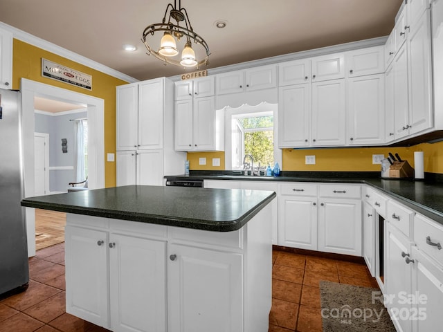 kitchen featuring dark countertops, freestanding refrigerator, a center island, white cabinetry, and a sink