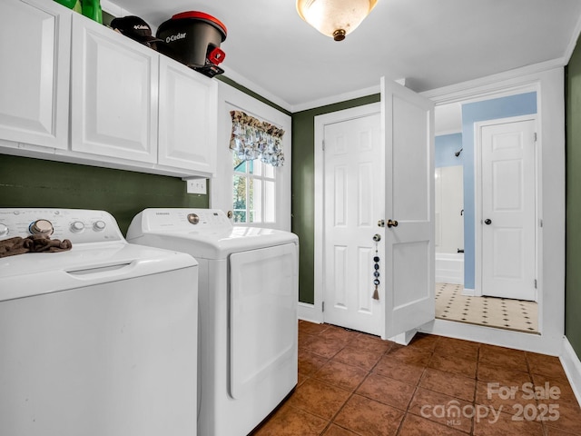 clothes washing area with dark tile patterned flooring, cabinet space, washer and clothes dryer, and baseboards