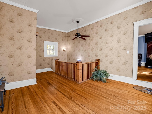 interior space featuring wallpapered walls, baseboards, ornamental molding, and hardwood / wood-style flooring