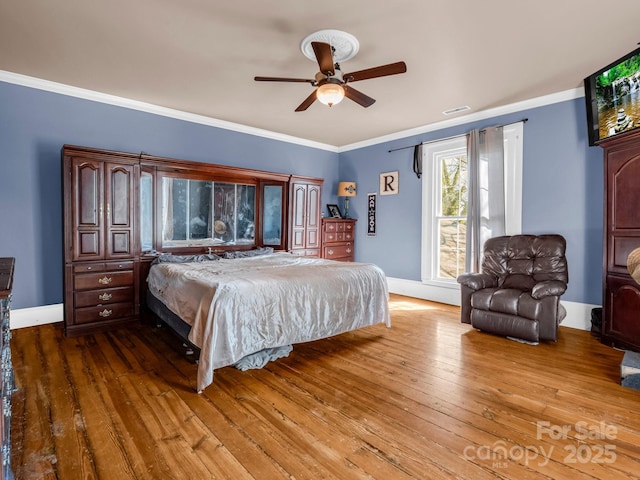 bedroom with baseboards, visible vents, ceiling fan, ornamental molding, and hardwood / wood-style floors