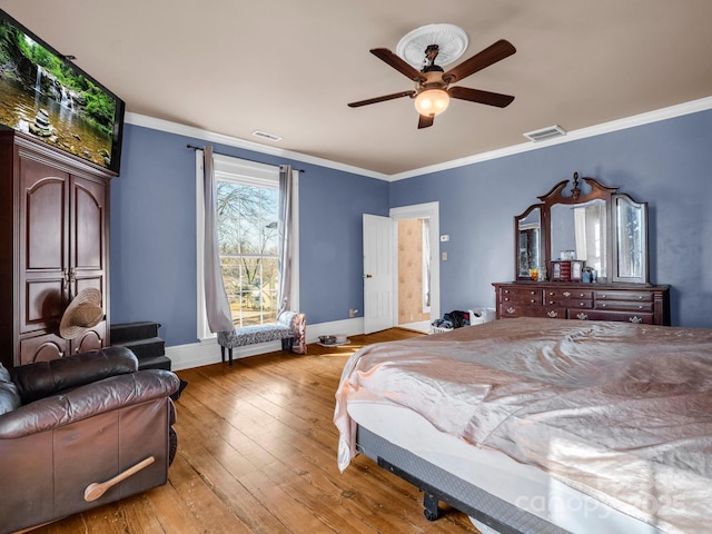 bedroom featuring light wood finished floors, ornamental molding, visible vents, and baseboards