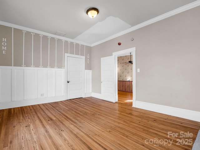 spare room featuring baseboards, wood finished floors, and crown molding