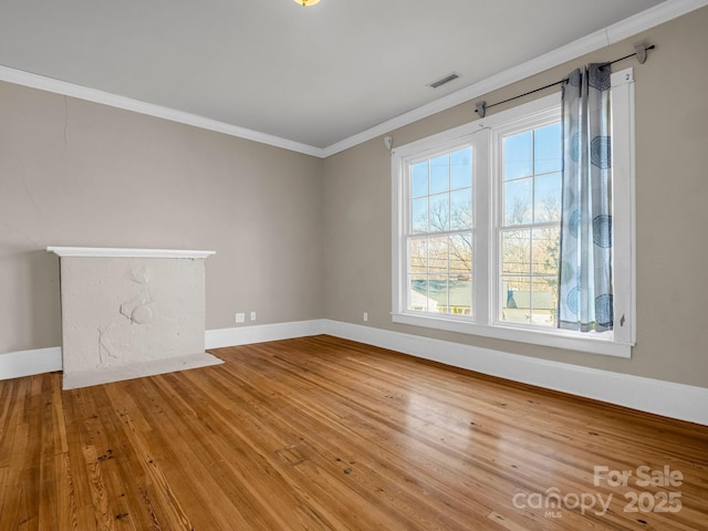 unfurnished living room featuring baseboards, wood-type flooring, visible vents, and crown molding