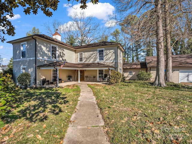 view of front of house featuring a patio area, a chimney, and a front lawn