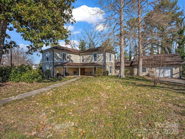 back of property with a garage, a chimney, and a yard