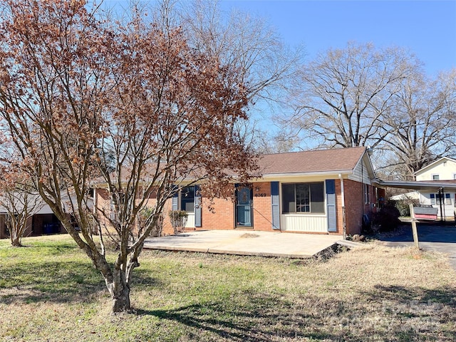 view of front of property with a carport, brick siding, a front lawn, and a shingled roof