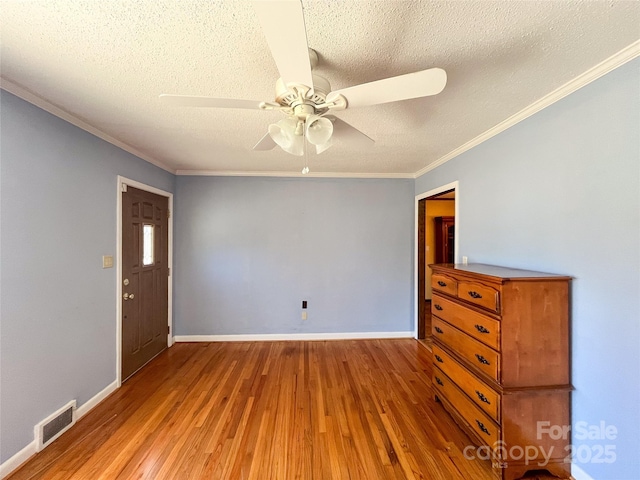 empty room with light wood-style flooring, a textured ceiling, visible vents, and baseboards