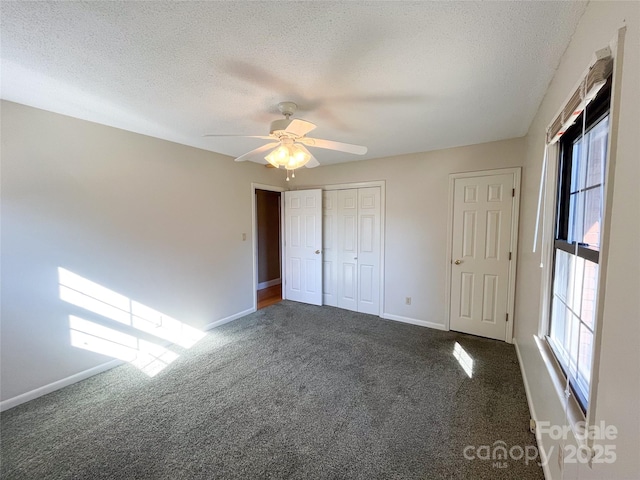 unfurnished bedroom featuring a textured ceiling, a ceiling fan, baseboards, a closet, and dark colored carpet