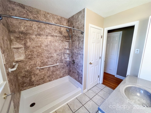 full bath with a stall shower, tile patterned flooring, a textured ceiling, and vanity