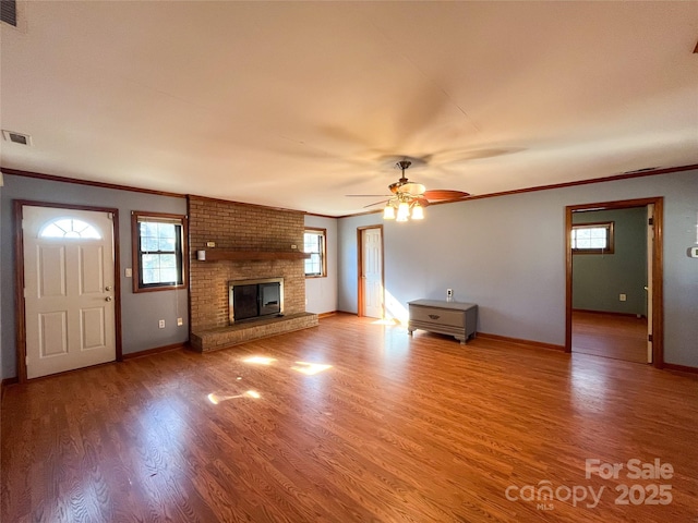 unfurnished living room featuring a wealth of natural light, a fireplace, and wood finished floors