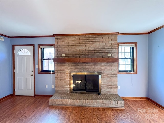 unfurnished living room with light wood-type flooring, a brick fireplace, baseboards, and crown molding