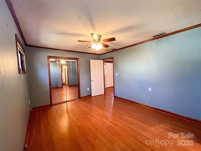 unfurnished bedroom featuring light wood-style floors, crown molding, and baseboards