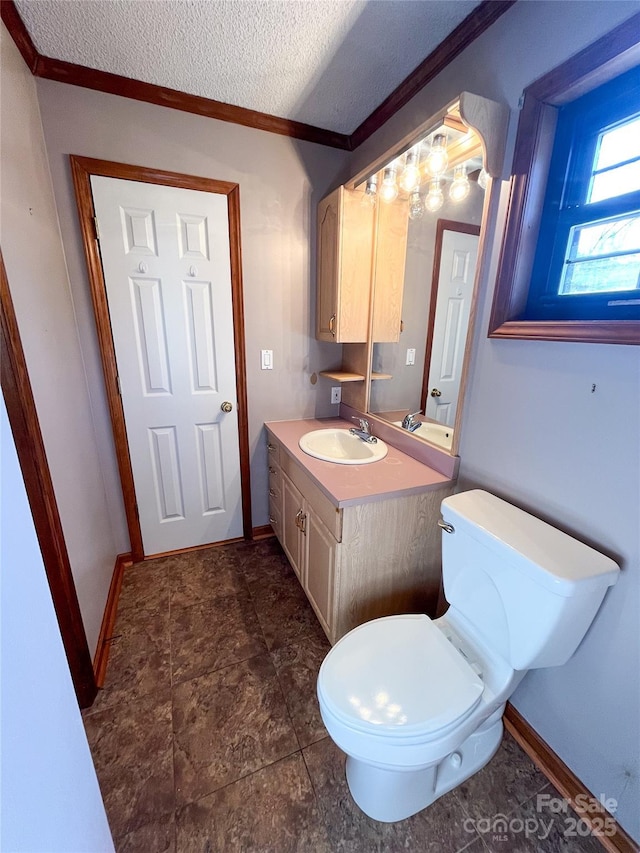 bathroom featuring crown molding, toilet, a textured ceiling, vanity, and baseboards