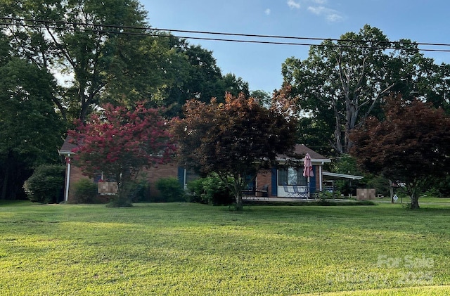 obstructed view of property featuring a front lawn and brick siding