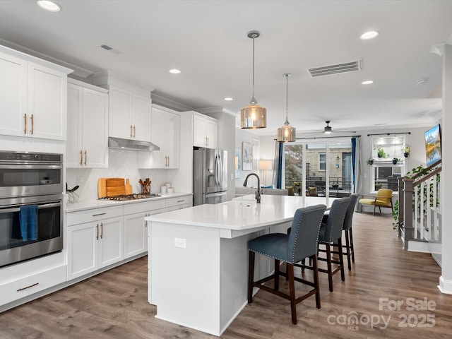 kitchen featuring white cabinets, stainless steel appliances, light countertops, and open floor plan