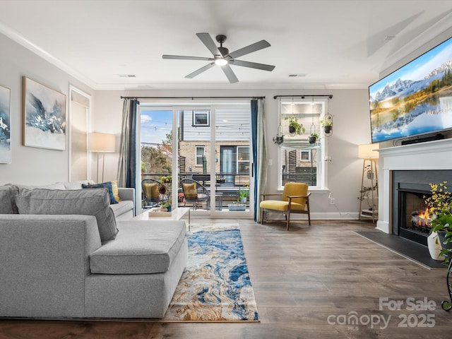 living room with a fireplace with flush hearth, ornamental molding, baseboards, and wood finished floors