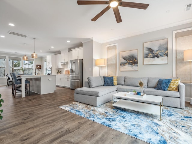 living room with ceiling fan, recessed lighting, dark wood-style flooring, visible vents, and crown molding