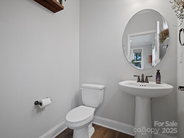 half bath featuring toilet, baseboards, and wood finished floors