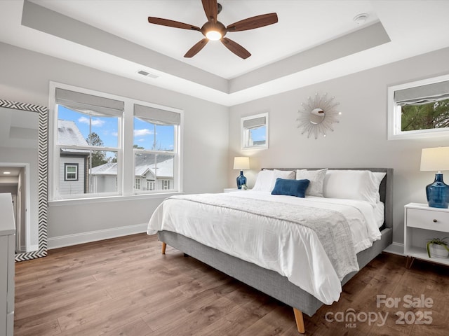 bedroom featuring visible vents, multiple windows, and a tray ceiling