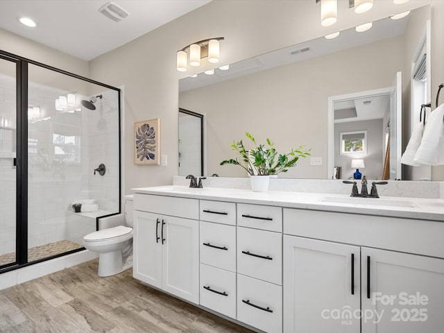 full bathroom with double vanity, visible vents, a sink, and wood finished floors