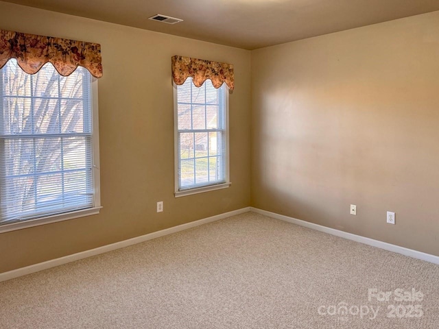 carpeted spare room featuring baseboards and visible vents