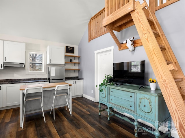 kitchen with dark wood-type flooring, lofted ceiling, white cabinets, and stainless steel refrigerator