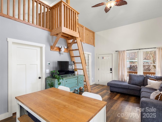 living room with dark wood-type flooring, a towering ceiling, and ceiling fan