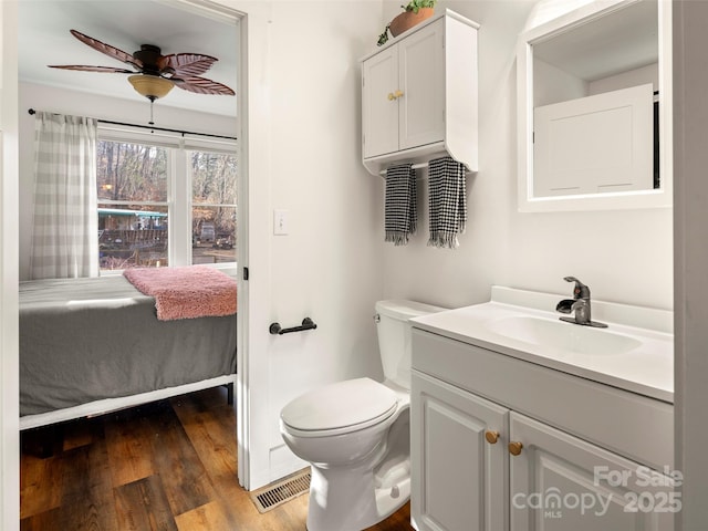 bathroom with toilet, hardwood / wood-style flooring, ceiling fan, and vanity