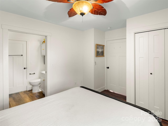 bedroom with dark wood-type flooring, ensuite bathroom, ceiling fan, and a closet