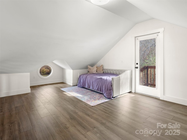 unfurnished bedroom featuring access to exterior, hardwood / wood-style flooring, and vaulted ceiling