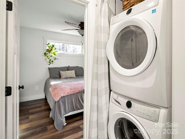 clothes washing area featuring ceiling fan, stacked washer and clothes dryer, and dark hardwood / wood-style flooring