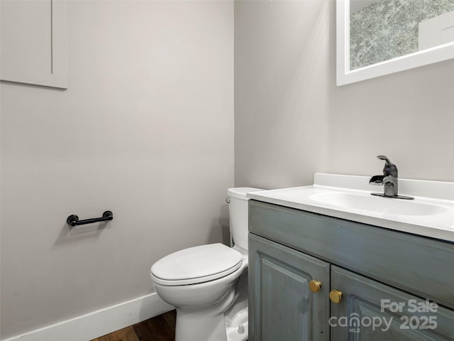 bathroom with hardwood / wood-style flooring, toilet, and vanity