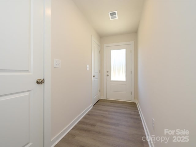 doorway featuring wood finished floors, visible vents, and baseboards