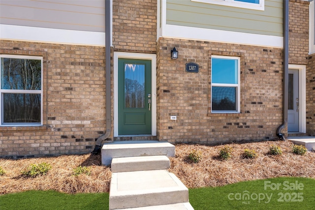 view of exterior entry featuring crawl space and brick siding