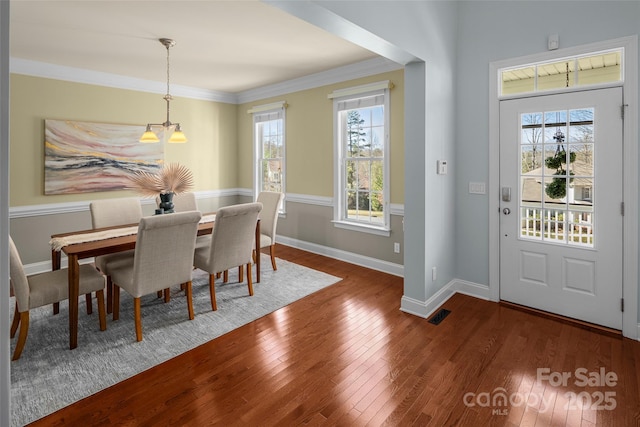 dining room featuring baseboards, wood-type flooring, and ornamental molding