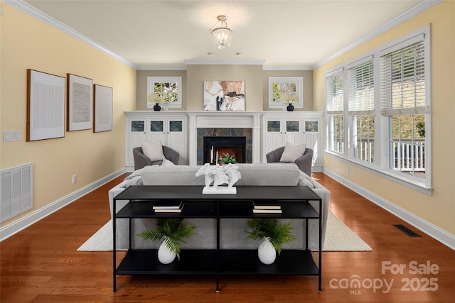 living area featuring crown molding, wood finished floors, visible vents, and a tile fireplace