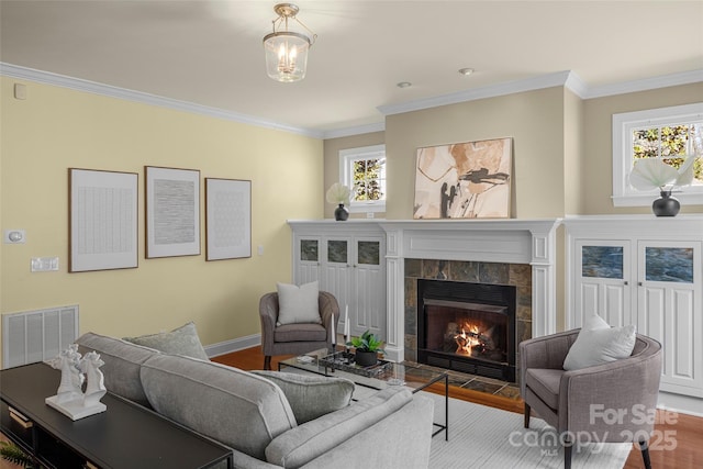 living room featuring plenty of natural light, wood finished floors, visible vents, and a tile fireplace