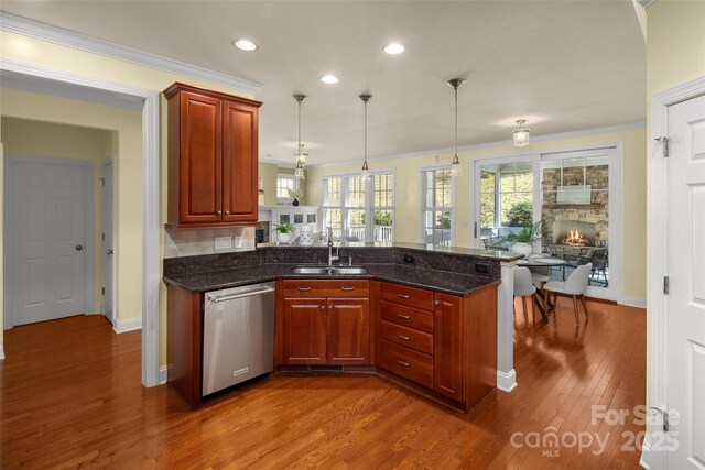 kitchen with a sink, wood finished floors, a peninsula, crown molding, and dishwasher