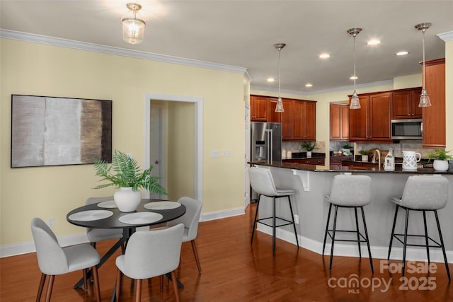 kitchen featuring decorative backsplash, a breakfast bar area, stainless steel appliances, and dark wood-type flooring