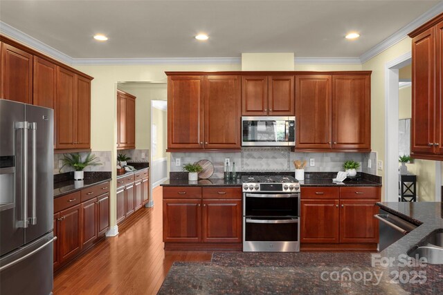 kitchen with stainless steel appliances, wood finished floors, decorative backsplash, and crown molding