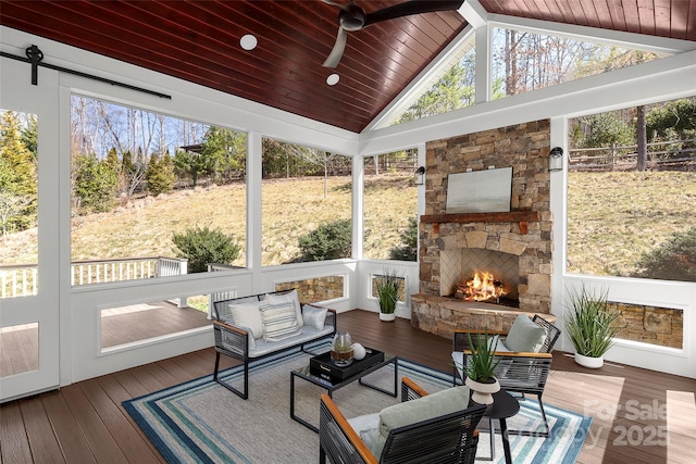 sunroom with a fireplace, wood ceiling, a ceiling fan, and vaulted ceiling