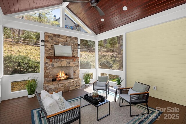 sunroom / solarium featuring a ceiling fan, wood ceiling, a fireplace, and vaulted ceiling