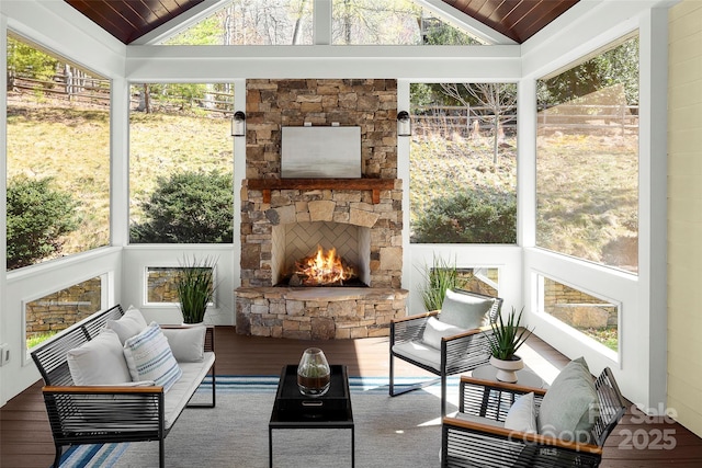 sunroom featuring a stone fireplace, vaulted ceiling, and wooden ceiling