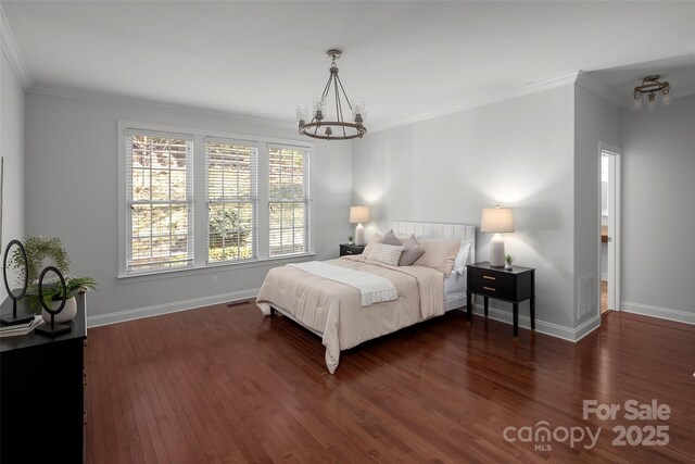 bedroom with dark wood finished floors, crown molding, and baseboards