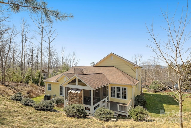 back of house featuring a yard, cooling unit, a sunroom, and roof with shingles