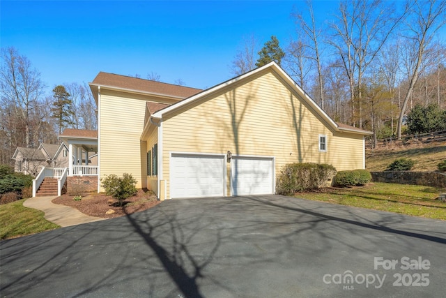 view of side of property with a garage, covered porch, and driveway