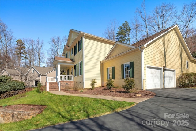 view of side of property featuring crawl space, covered porch, driveway, and a lawn