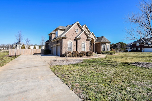 view of front of property featuring concrete driveway, brick siding, a front lawn, and fence